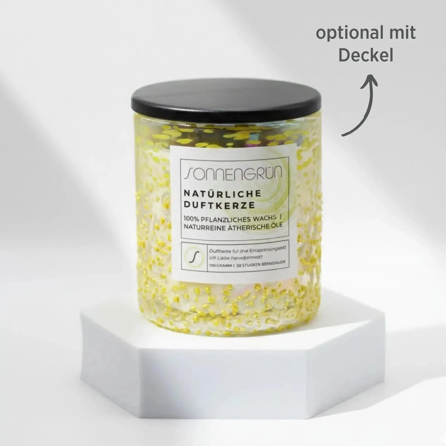 Auf diesem Foto sieht man die Duftkerze von Sonnengrün in einem grünem Glas auf einem weißen Podest stehen. Die Naturkerze ist mit einem Holzdeckel verschlossen, was mit dunkler Schrift gekennzeichnet ist ("optional mit Decke").