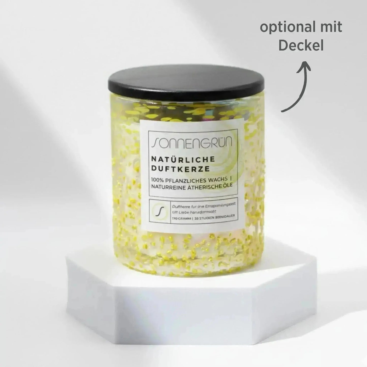 Auf diesem Foto sieht man die Duftkerze von Sonnengrün in einem gelben Glas auf einem weißen Podest stehen. Die Naturkerze ist mit einem Holzdeckel verschlossen, was mit dunkler Schrift gekennzeichnet ist ("optional mit Decke").