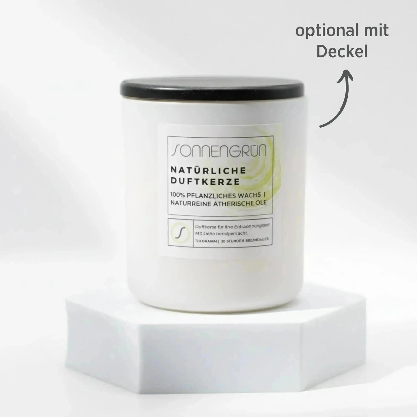 Auf diesem Foto sieht man die Duftkerze von Sonnengrün in einem weißem Glas auf einem weißen Podest stehen. Die Naturkerze ist mit einem Holzdeckel verschlossen, was mit dunkler Schrift gekennzeichnet ist ("optional mit Decke").