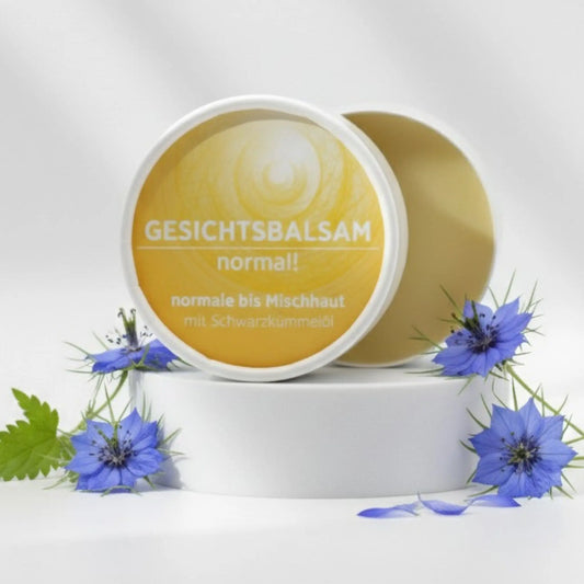 Gesichtsbalsam mit natürlichen Inhaltsstoffen für normale Haut mit Schwarzkümmelöl, Gesichtsbalsam ist in weißem, zylindrischem Karton verpackt mit gelbem Etikett, zudem sind detaillierte Produktinformationen am Bild zu lesen.