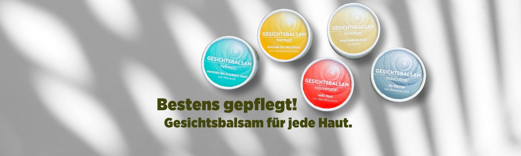 Auf dem Banner sieht man die bunt verpackten Gesichtscremen von Sonnengrün in den Kartonagen mit farbigen Etiketten in Türkis, Gelb, Rot, Beige und Dunkelblau vor einer weißen Wand mit Schattenspiel. Mit dunkelgrüner Schrift ist zu lesen "Bestens gepflegt! Gesichtsbalsam für jede Haut."