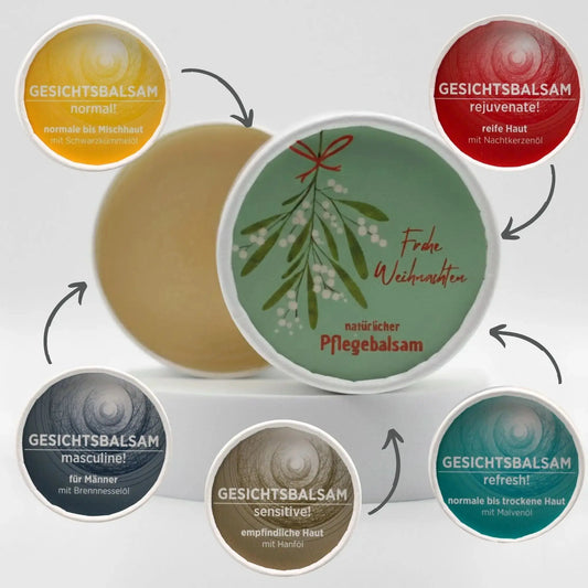 Auf dem Bild sieht man den Pflegebalsam mit einem Etikett, gestaltet speziell für Weihnachten. Rund um den Tiegel sind die diversen Sorten der Gesichtsbalsame mit Pfeil auf den Tiegel, was symbolisiert, dass die Gesichtsbalsame mit dem Etikett personalisiert werden können.