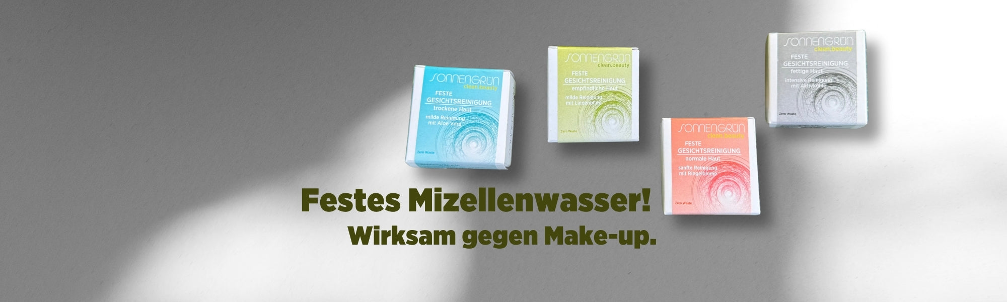 Auf dem Banner sieht man die bunt verpackten festen Gesichtsreinigungen von Sonnengrün in den farbigen Kartonagen Orange, Türkis, Grün und Schwarz vor einer weißen Wand mit Schattenspiel. Mit dunkelgrüner Schrift ist zu lesen "Festes Mizellenwasser! Wirksam gegen Make-Up."