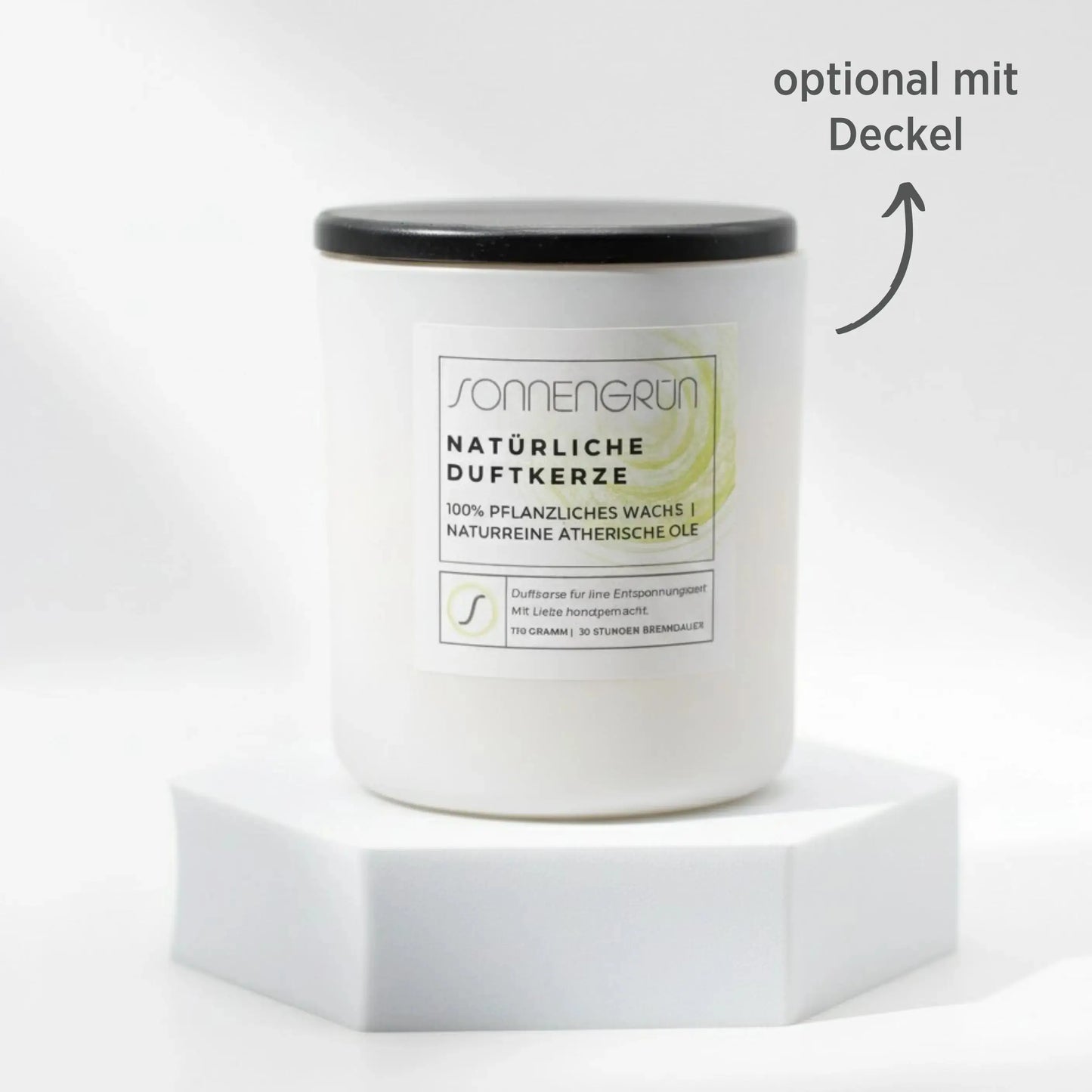 Auf diesem Foto sieht man die Duftkerze von Sonnengrün in einem weißem Glas auf einem weißen Podest stehen. Die Naturkerze ist mit einem Holzdeckel verschlossen, was mit dunkler Schrift gekennzeichnet ist ("optional mit Decke").