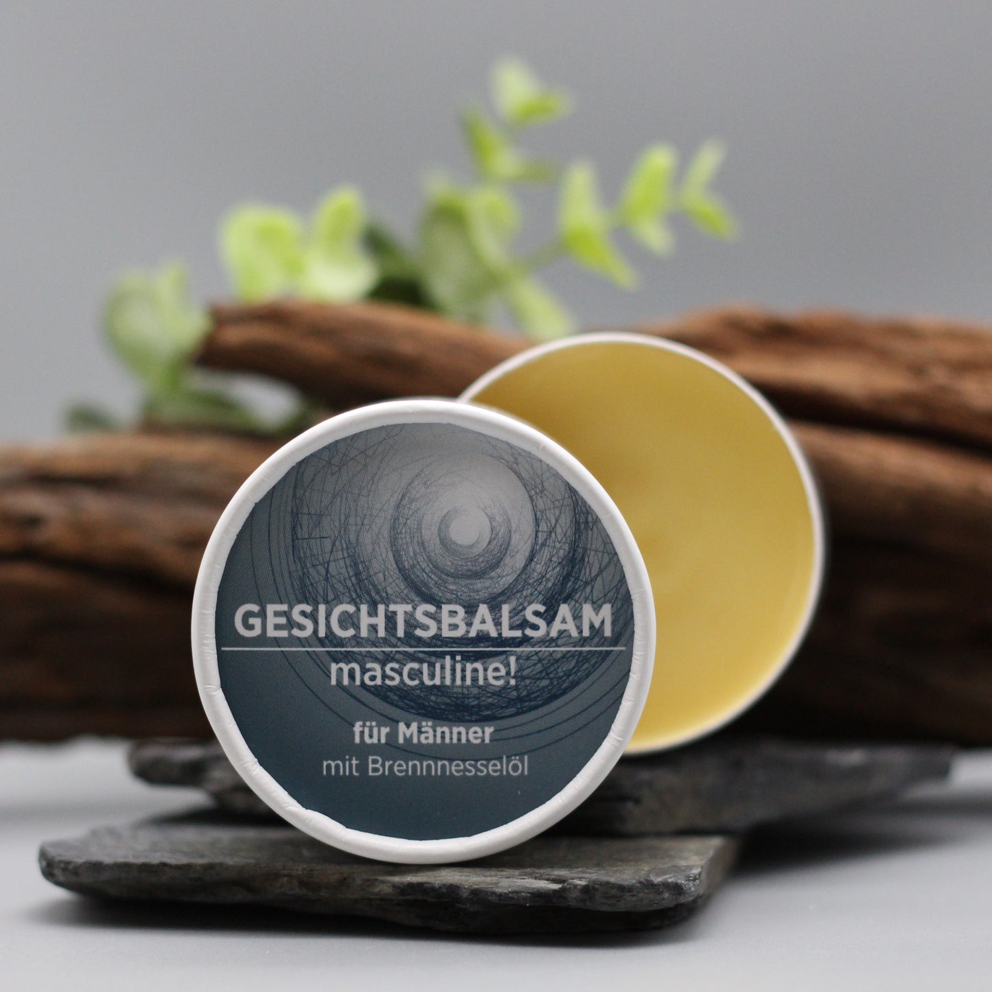 Gesichtsbalsam mit natürlichen Inhaltsstoffen für Männer, Gesichtsbalsam ist in weißem, zylindrischem Karton verpackt mit dunklem Etikett.