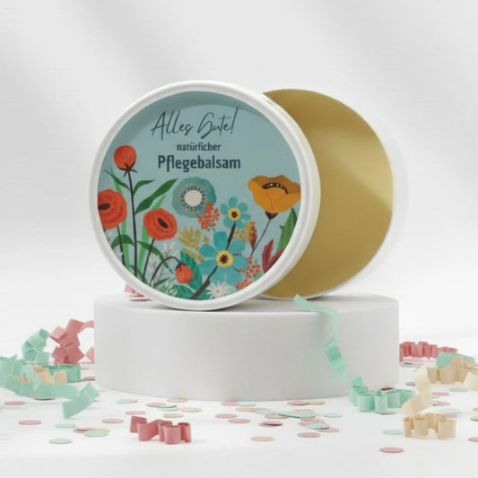 Auf dem Bild sieht man den Pflegebalsam mit einem Etikett, gestaltet speziell für Geburtstage. Auf dem Etikett sich man bunte Blumen abgebildet und die Aufschrift "Alles Gute!" und "natürlicher Pflegebalsam". Das Etikett macht den Körperbalsam zum perfekten Geburtstagsgeschenk.