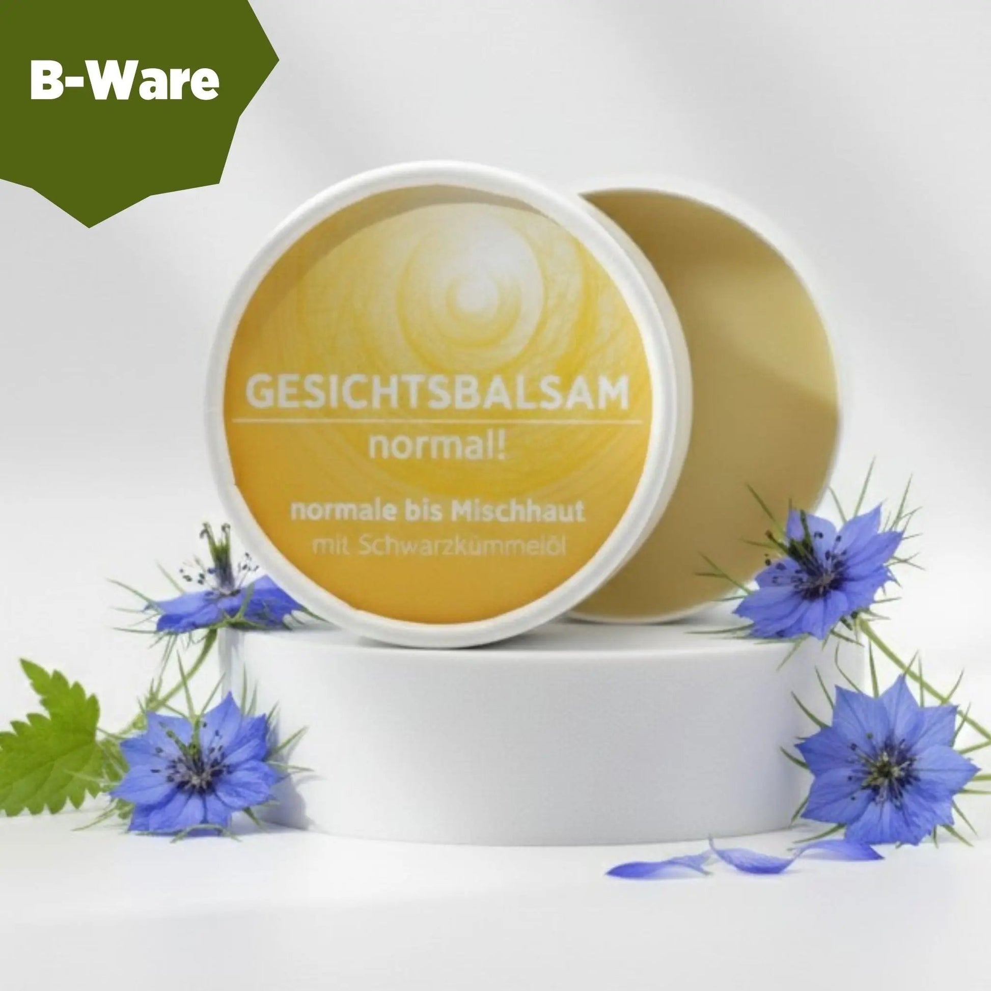 Gesichtsbalsam mit natürlichen Inhaltsstoffen für normale Haut mit Schwarzkümmelöl, Gesichtsbalsam ist in weißem, zylindrischem Karton verpackt mit gelbem Etikett, zudem sind detaillierte Produktinformationen am Bild zu lesen. B-Ware, Verpackung beschädigt.