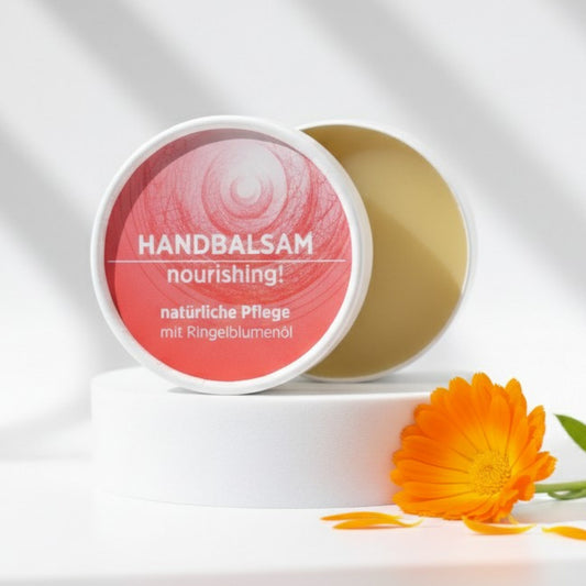 Handbalsam mit natürlichen Inhaltsstoffen für trockene Hände mit Ringelblume, Balsam ist in weißem, zylindrischem Karton verpackt mit rotem Etikett.