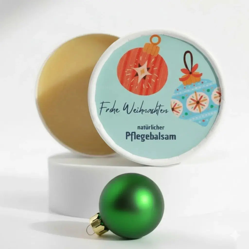 Auf dem Bild sieht man den Pflegebalsam mit einem Etikett, gestaltet speziell für Weihnachten. Auf dem Etikett sieht man ein Weihnachtsmotiv abgebildet und die Aufschrift "Frohe Weihnachten" und "natürlicher Pflegebalsam". Das Etikett macht den Körperbalsam zum perfekten Weihnachtsgeschenk.