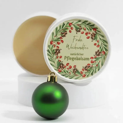 Auf dem Bild sieht man den Pflegebalsam mit einem Etikett, gestaltet speziell für Weihnachten. Auf dem Etikett sieht man ein Weihnachtsmotiv abgebildet und die Aufschrift "Frohe Weihnachten" und "natürlicher Pflegebalsam". Das Etikett macht den Körperbalsam zum perfekten Weihnachtsgeschenk.
